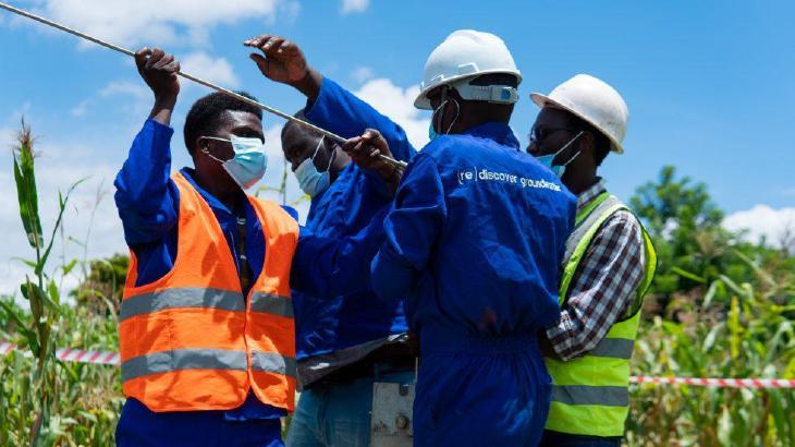 workers in blue jumpsuits replacing well equipment