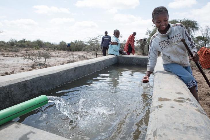 child reaching into well